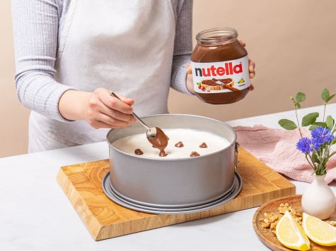 Using a small spoon the backer is placing dollops of Nutella® into the filling, making sure there's some space between the dollops.